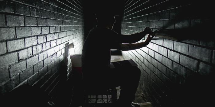 6901x4606 silhouette photograph of man sitting on crate while fixing the wall