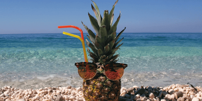 1920x1080 Vacation concept - Pineapple wearing sunglasses on a beautiful pebble beach  next to crystal clear turquoise water Stock Video Footage - Storyblocks