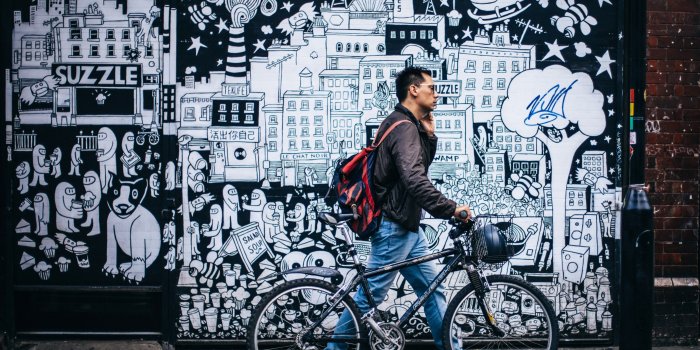 3840x3051 man walking on sidewalk with bike past black and white cartoon