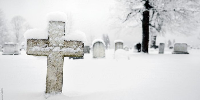 1200x801 Cross gravestone in a snowy graveyard by Cara Dolan - Stocksy United