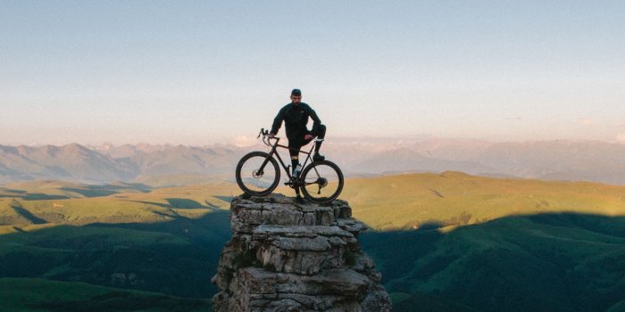 2048x1152 Download wallpaper 2048x1152 cyclist, bicycle, rock, peak, height