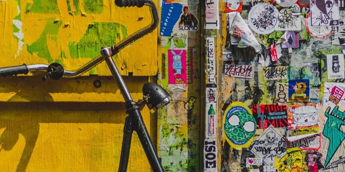 1242x2688 bike parked beside wall full of stickers iPhone X Wallpapers Free Download